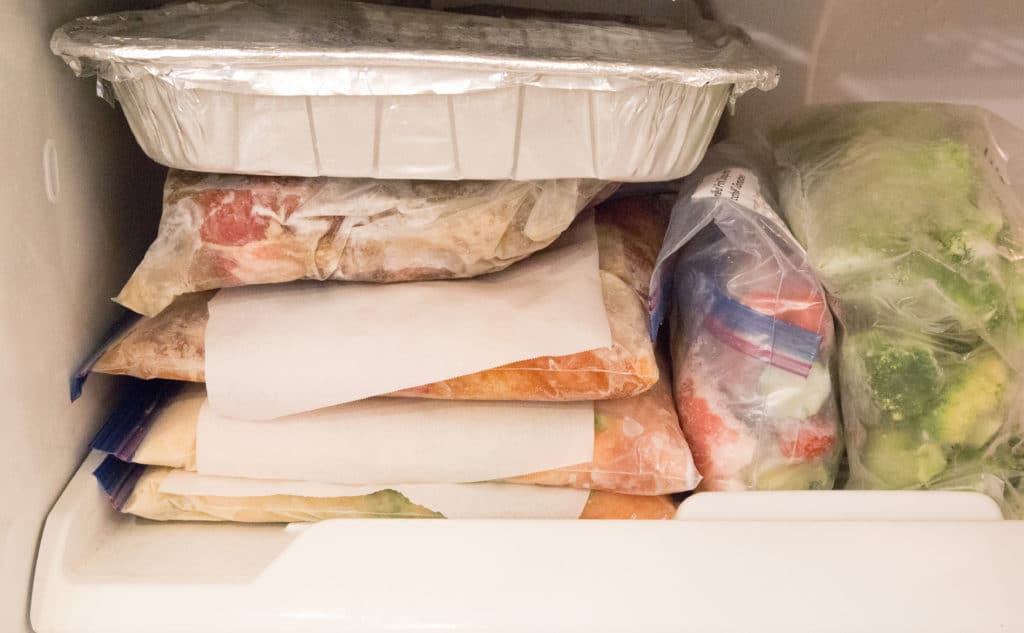 Freezer meals stacked with parchment paper